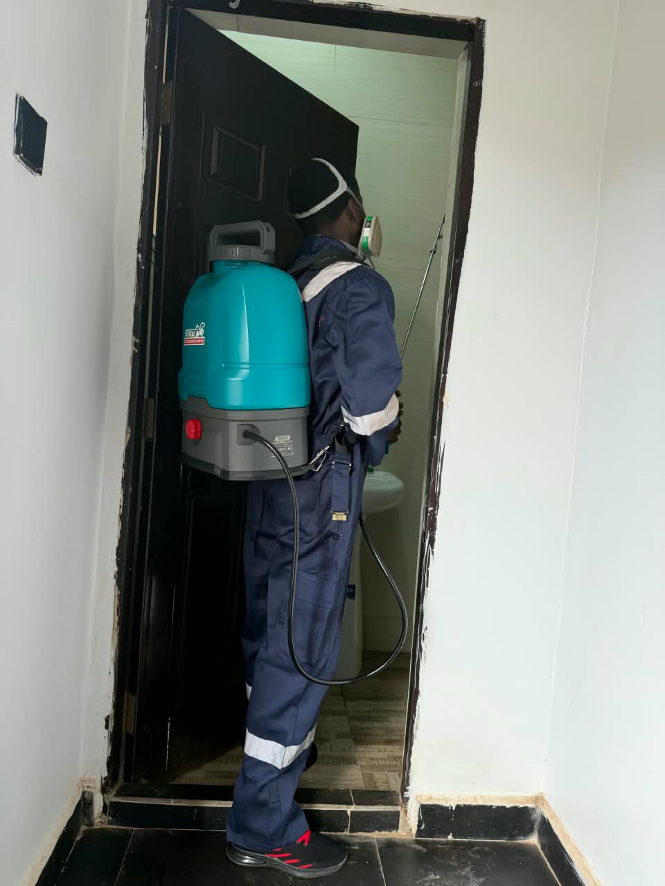 A worker in fumigation gear in a bathroom